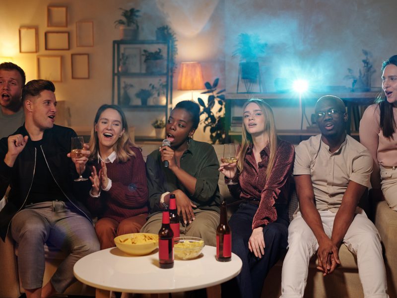 group-of-young-intercultural-friends-singing-karaoke-while-sitting-on-couch.jpg